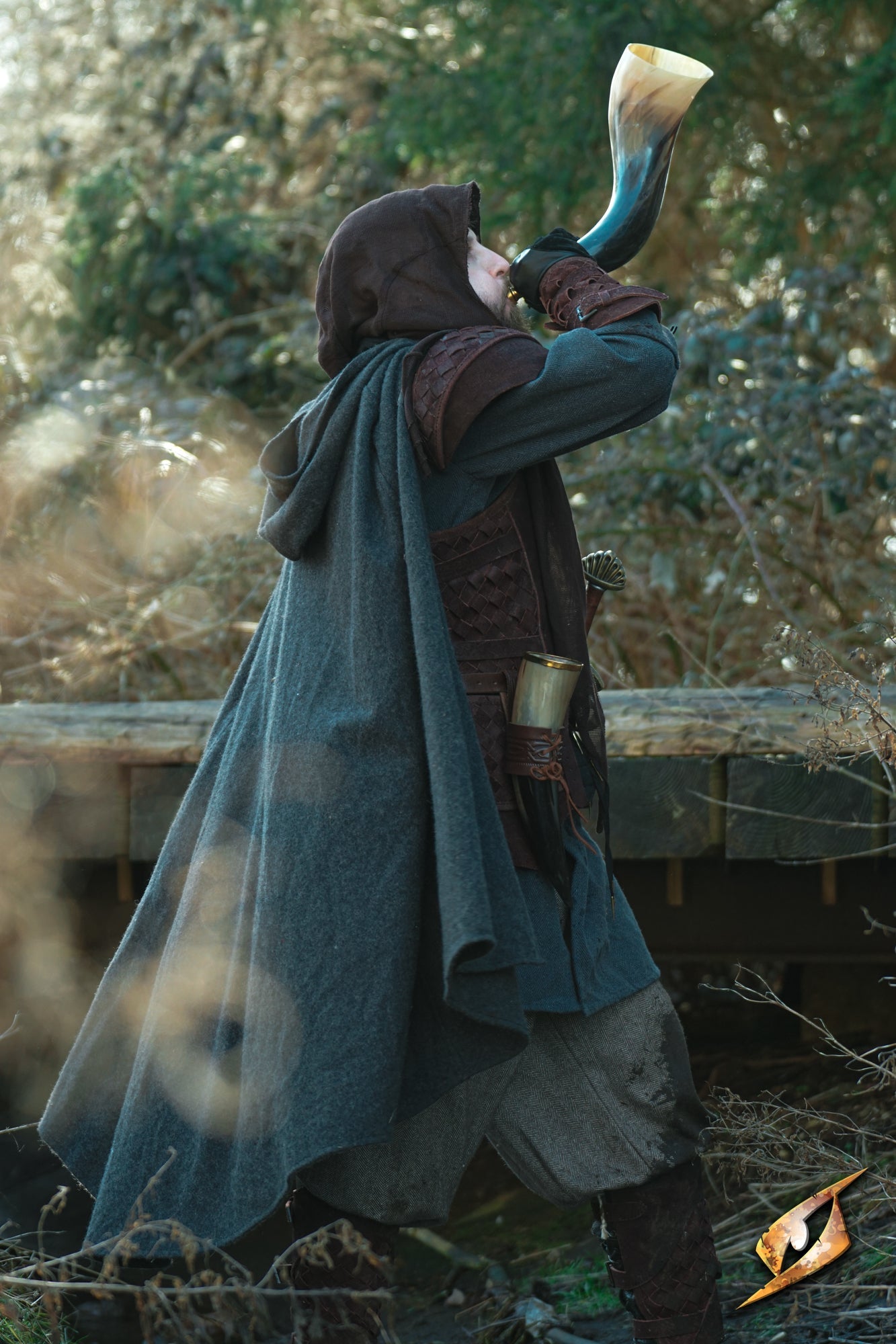 Person in a Cape Wool cape playing a horn outdoors, showcasing the garment's stylish design and functionality.