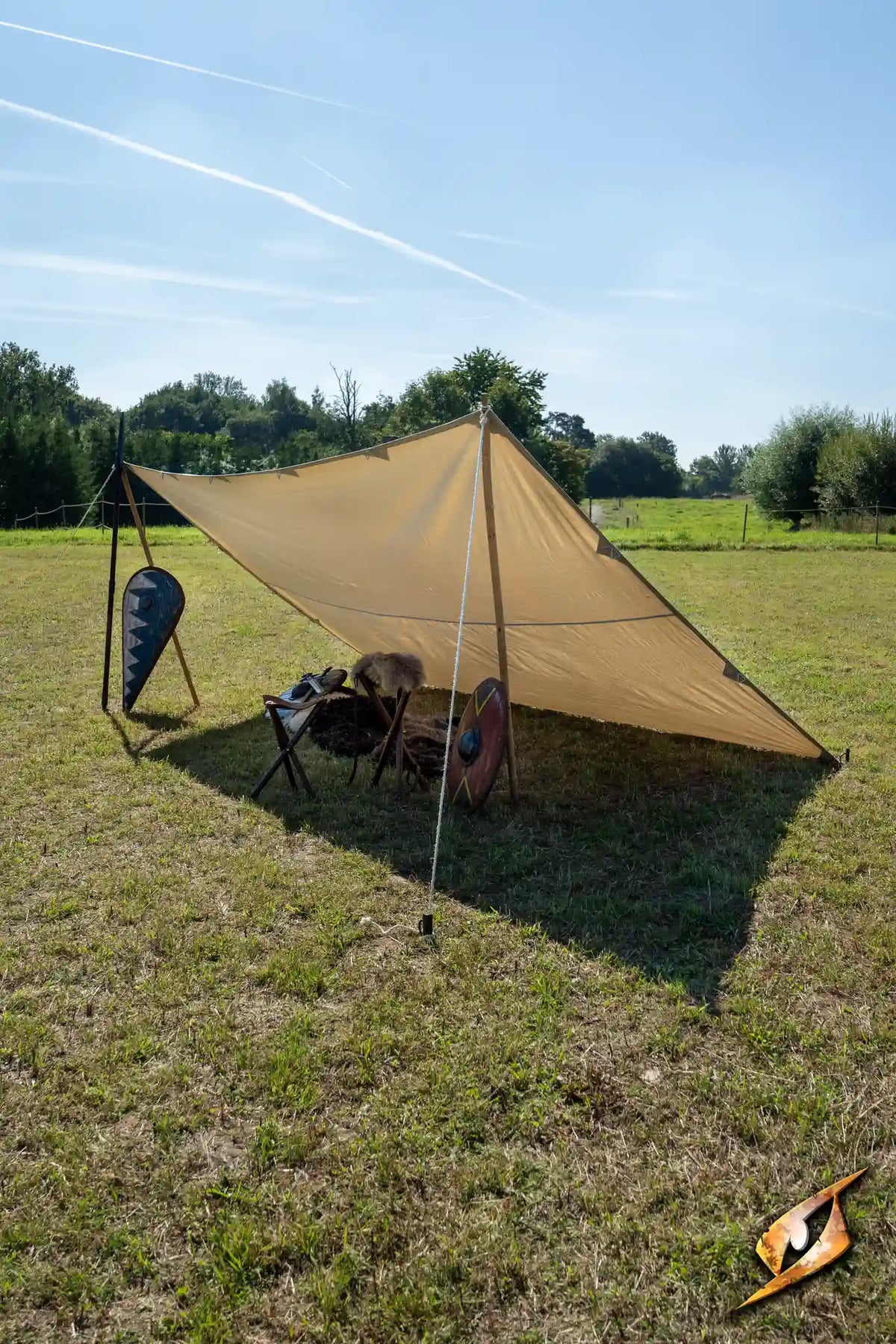 Tarpaulin setup providing shade on a sunny day in an open field, ideal for camping and outdoor activities.