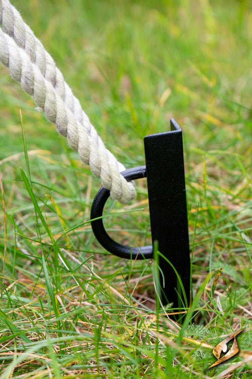 V-Shape Iron Peg A holding a rope in the grass, designed for stability and attachment in harsh conditions.