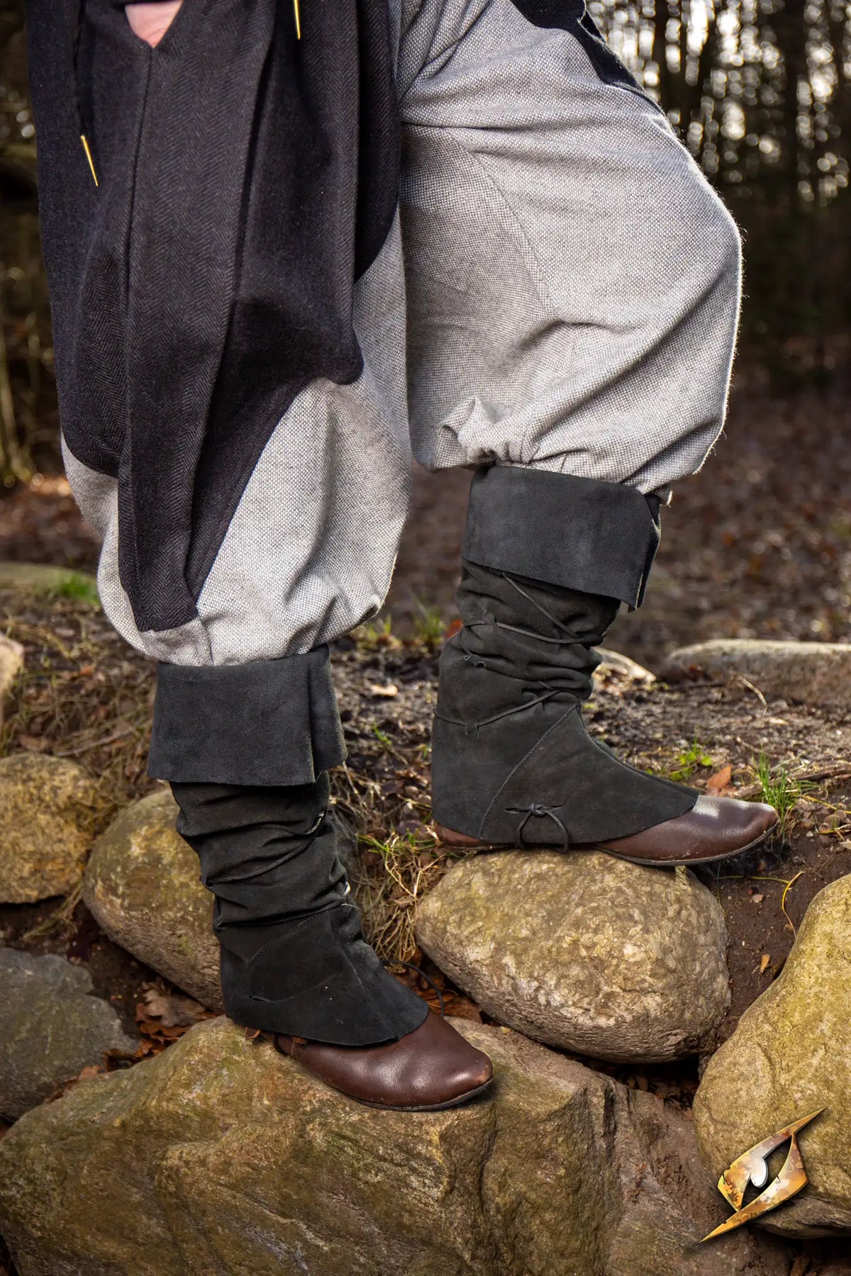 Theoderic gaiters worn over gray pants on a rocky surface in a forest setting.