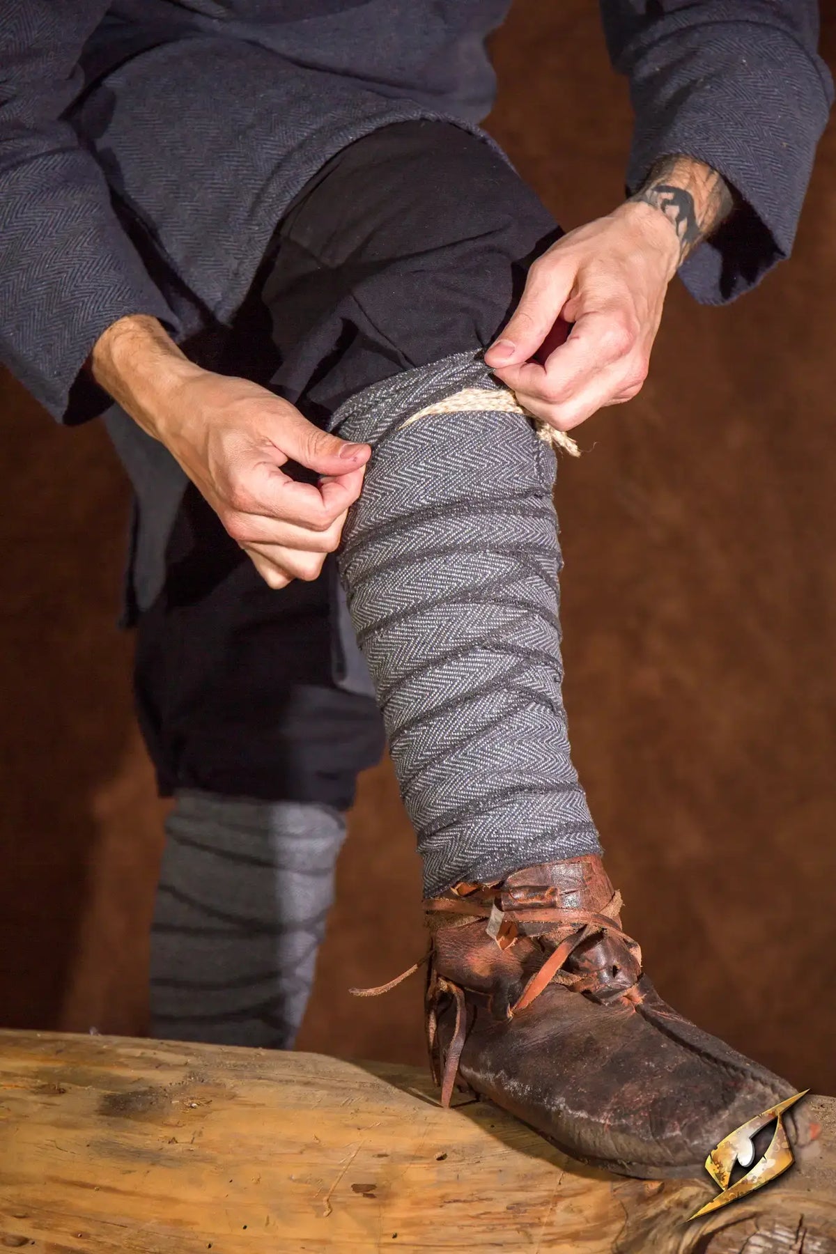 A person adjusting Woodland Leg Wraps, showcasing the fit and style of the leg wraps in a rustic setting.