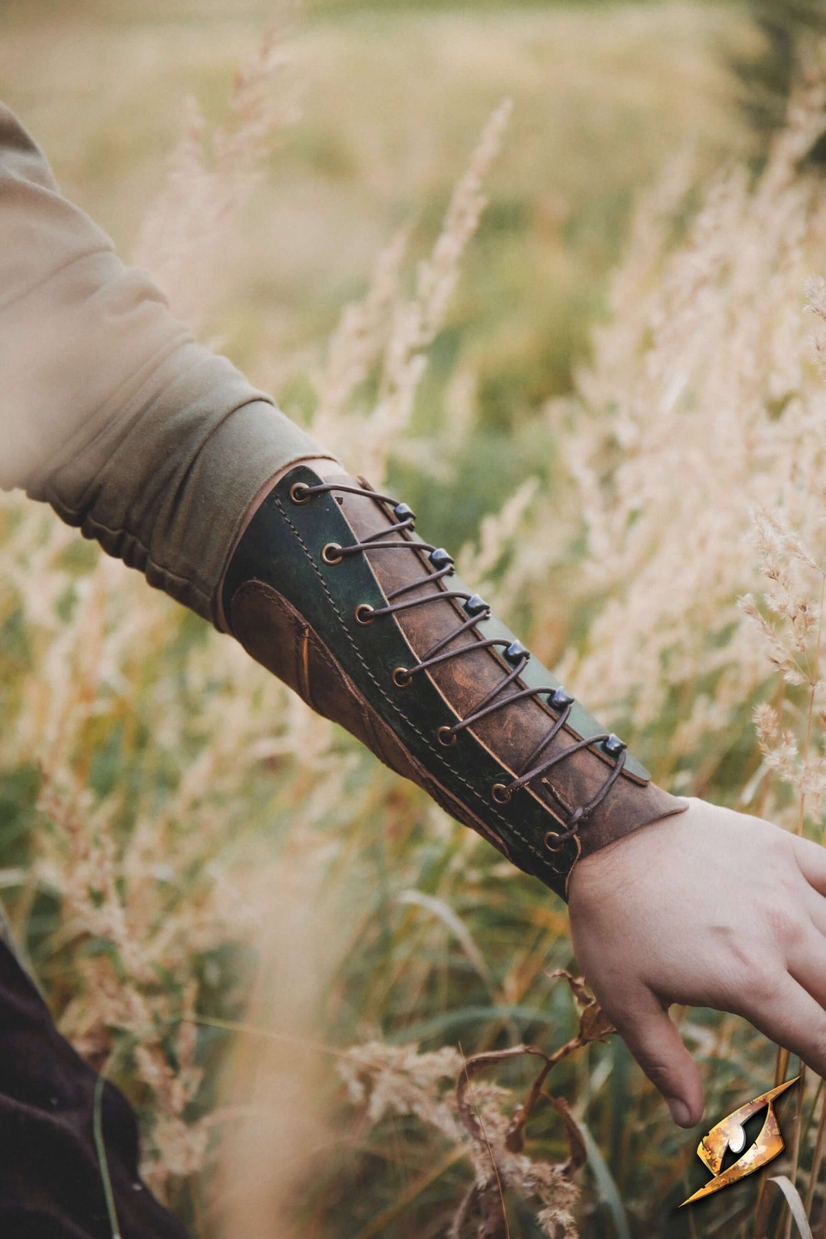 Glade Warden Bracer showcased on a forearm amidst tall grass, highlighting its elegant leather design and craftsmanship.