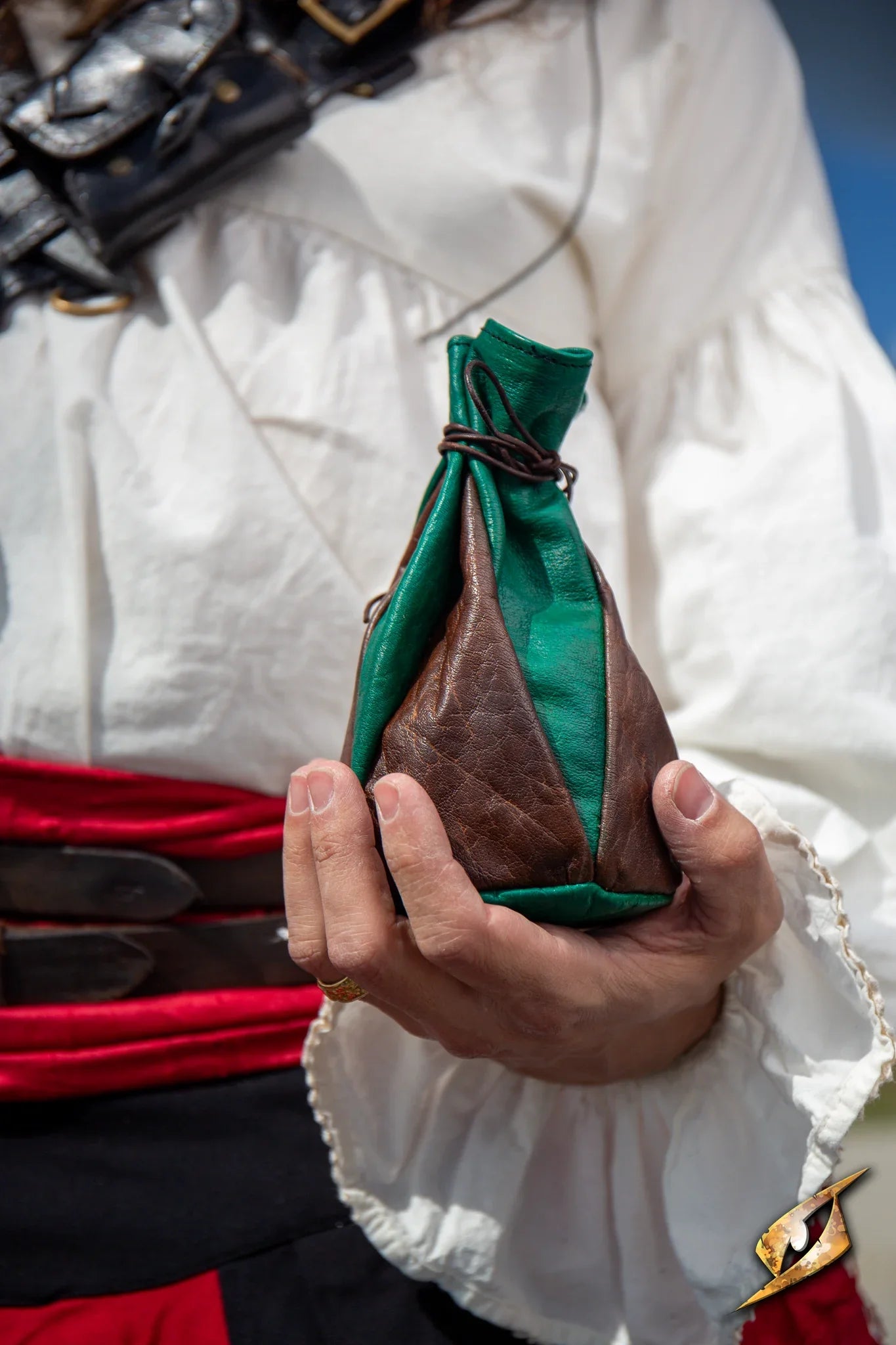 A person holding a Bounty Hunter Pouch in brown and green leather, ideal for carrying coins and essentials.