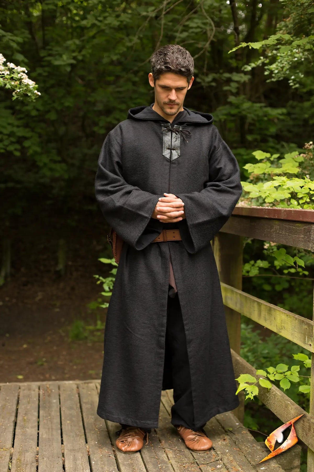 Robe Benedict worn by a man standing on a wooden bridge surrounded by greenery, evoking a mystical atmosphere.
