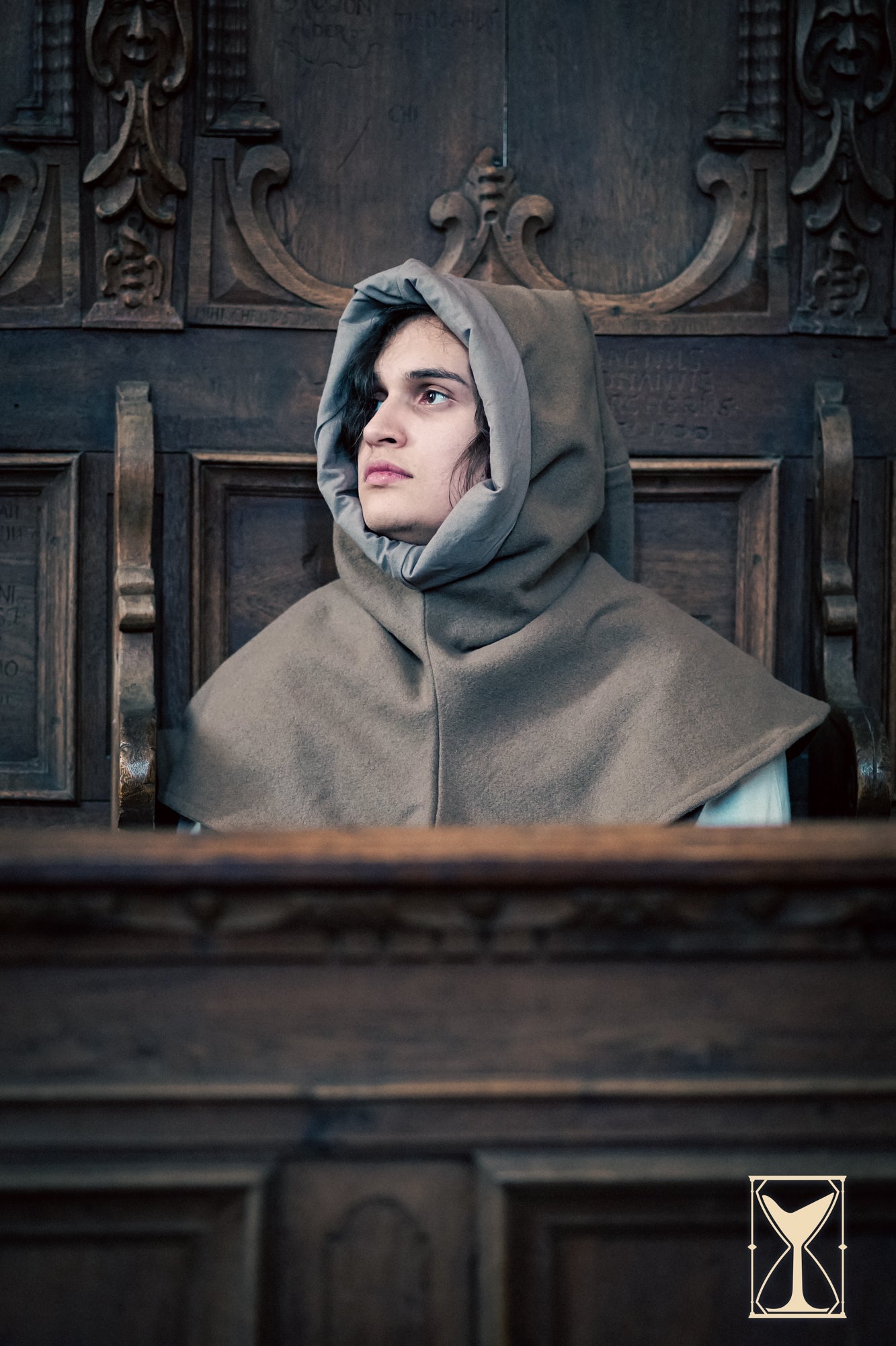 Simple Liripipe Hood - Brushed Wool worn by a person sitting in a medieval setting.
