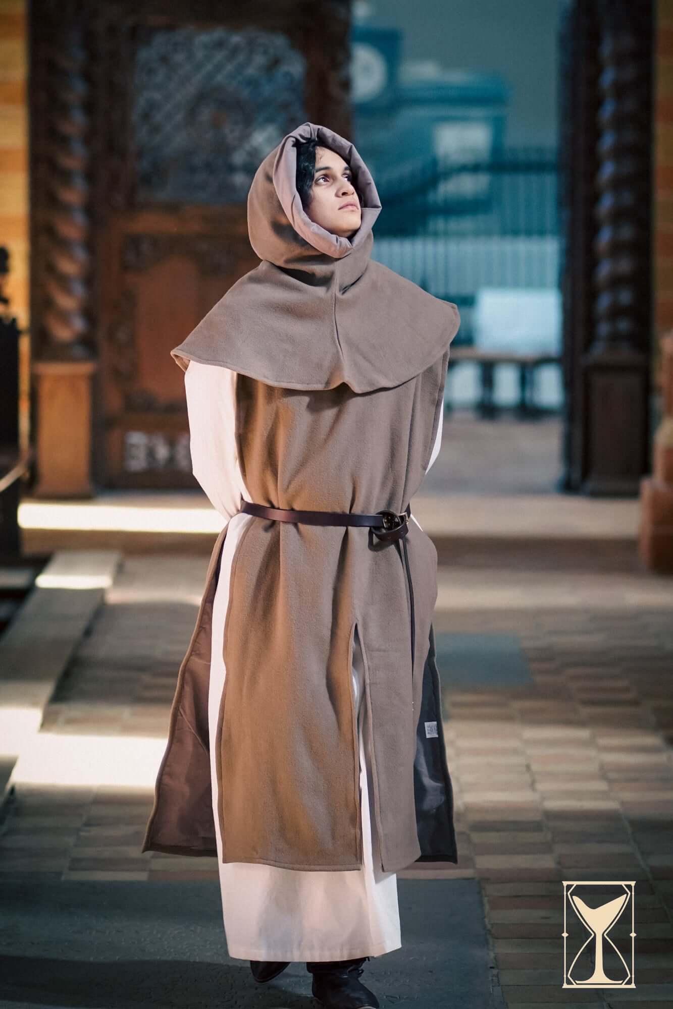 Model wearing Cyclas Bernard in a medieval setting, showcasing its layered design and historical style.