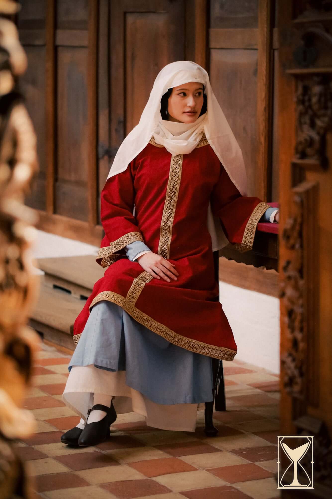 Overtunic Matilde worn by a model, showcasing wide sleeves and woven patterned trim in a historical setting.