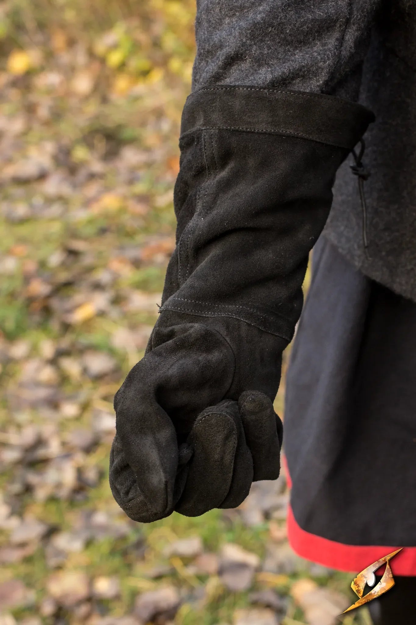 Close-up of a hand wearing stylish Leather Gloves outdoors on a forest floor.