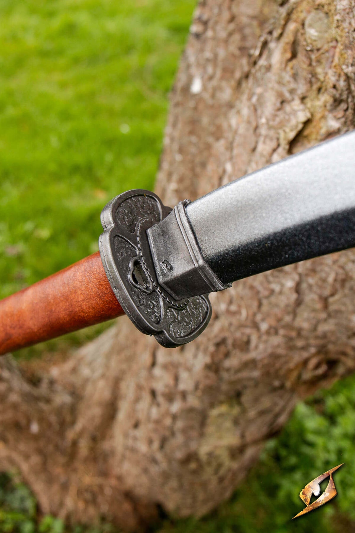 Mokko-gata Tsuba on a sword, showcasing its four-lobed melon design against a tree background.