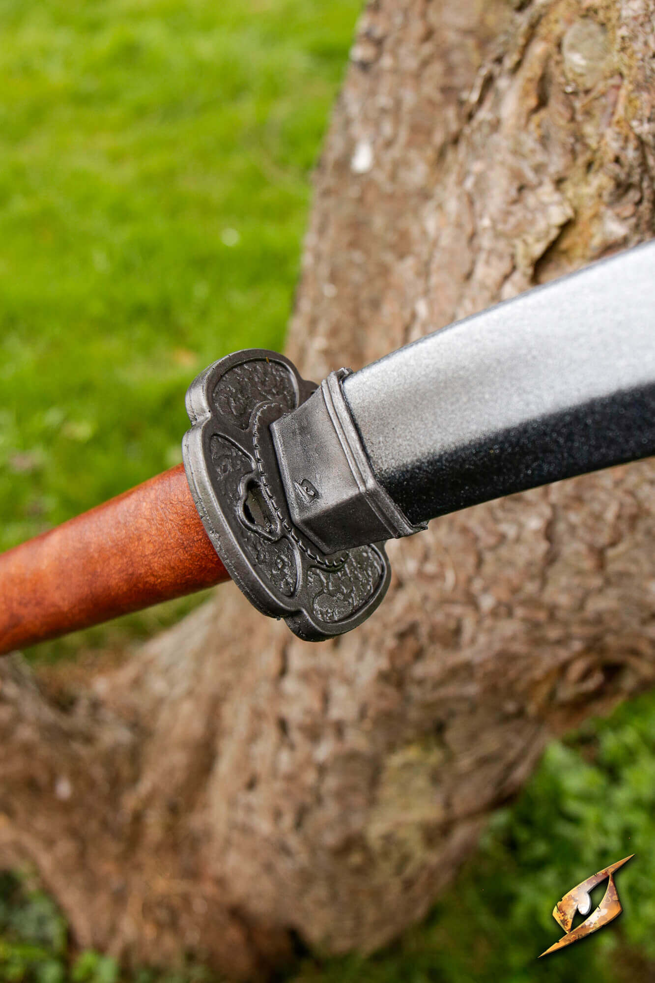 Mokko-gata Tsuba on a sword, showcasing its four-lobed melon design against a tree background.