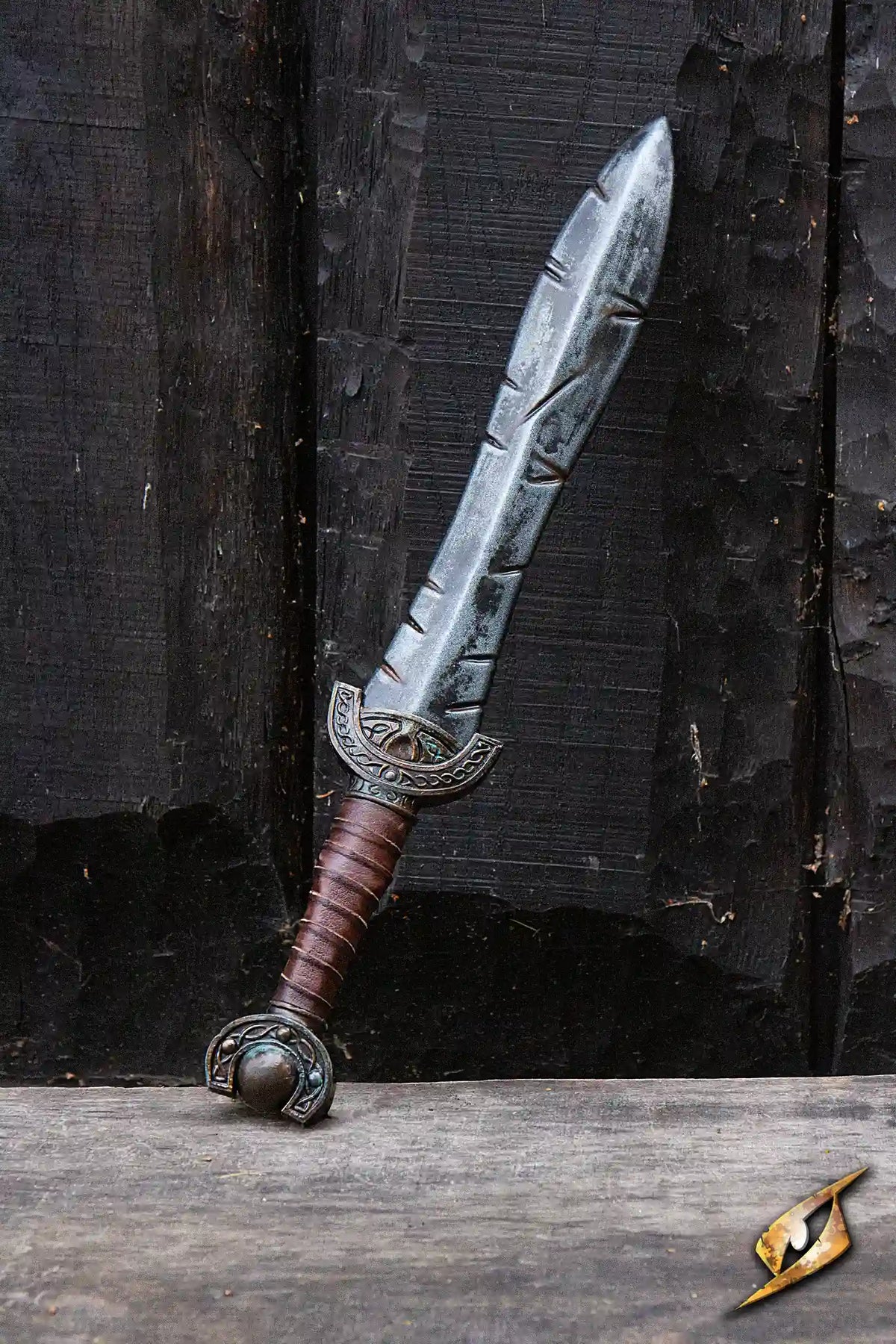 Battleworn Celtic Leaf Sword displayed against a wooden background, showcasing its aged, battle-worn details.