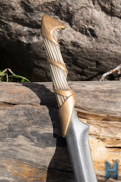 Elven Hunter Blade featuring a beautifully designed hilt resting on a log for outdoor adventures.
