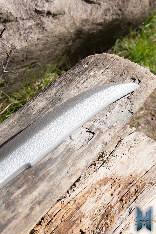 Elven Hunter Blade resting on a weathered log in a forest setting, showcasing its elegant design.
