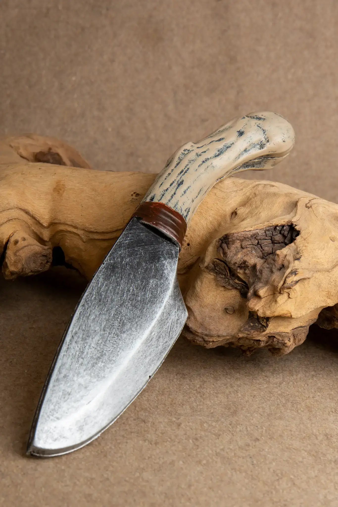 Wolfbane Throwing Knife with a distinctive bone handle resting on wood, designed for LARP and inspired by legends.