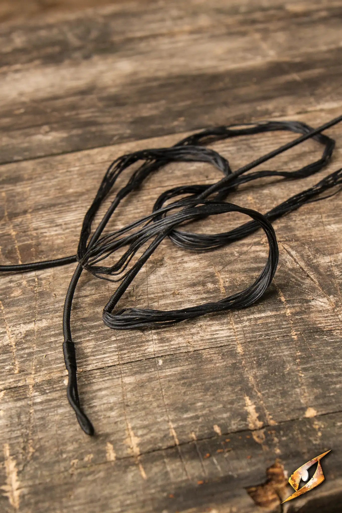 Bow String on a wooden surface, showcasing the durable replacement for Epic Armoury’s Medium LARP Flatbow.
