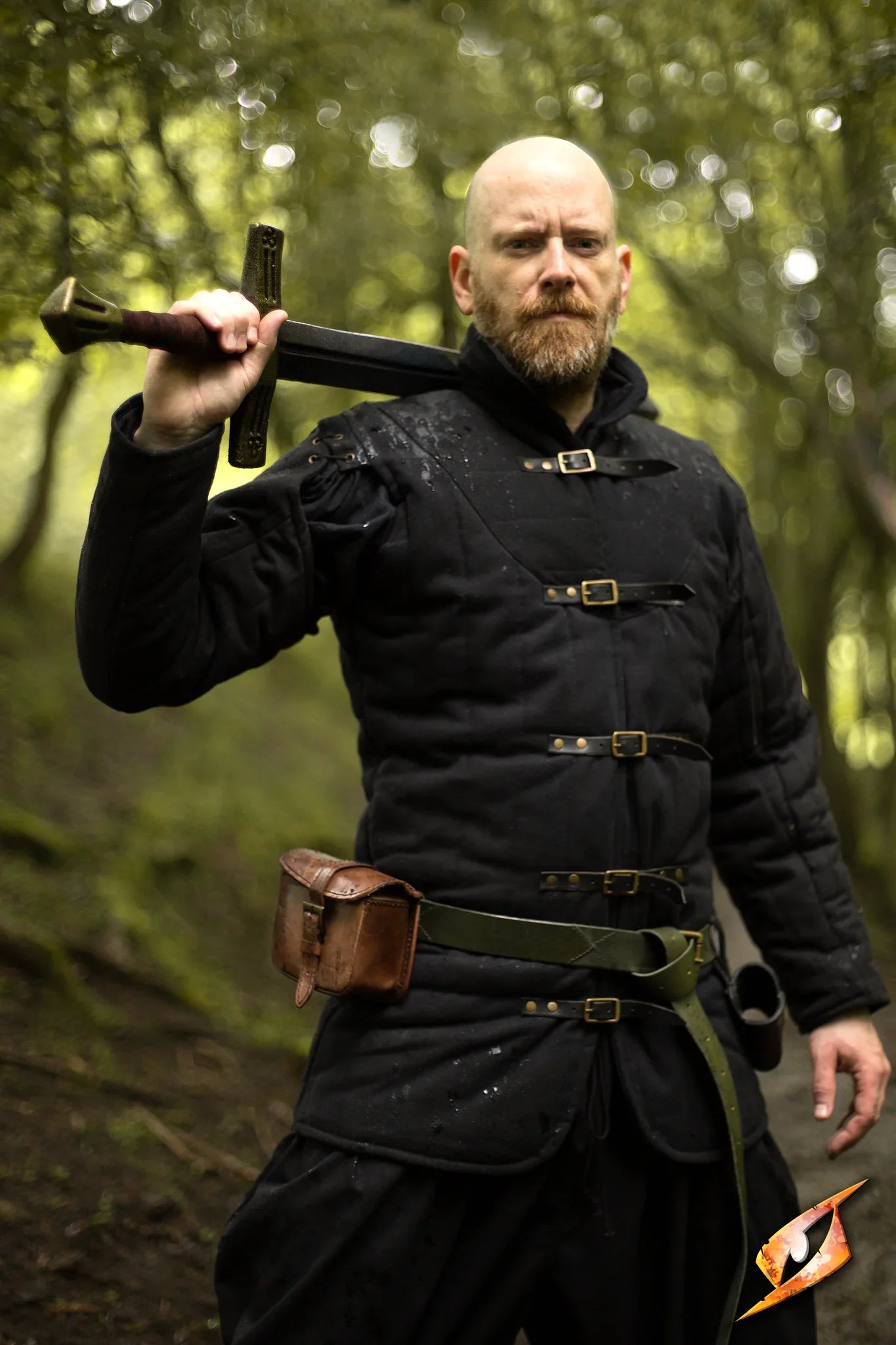 Gambeson Warrior With Long Sleeves stands confidently in the forest holding a sword.