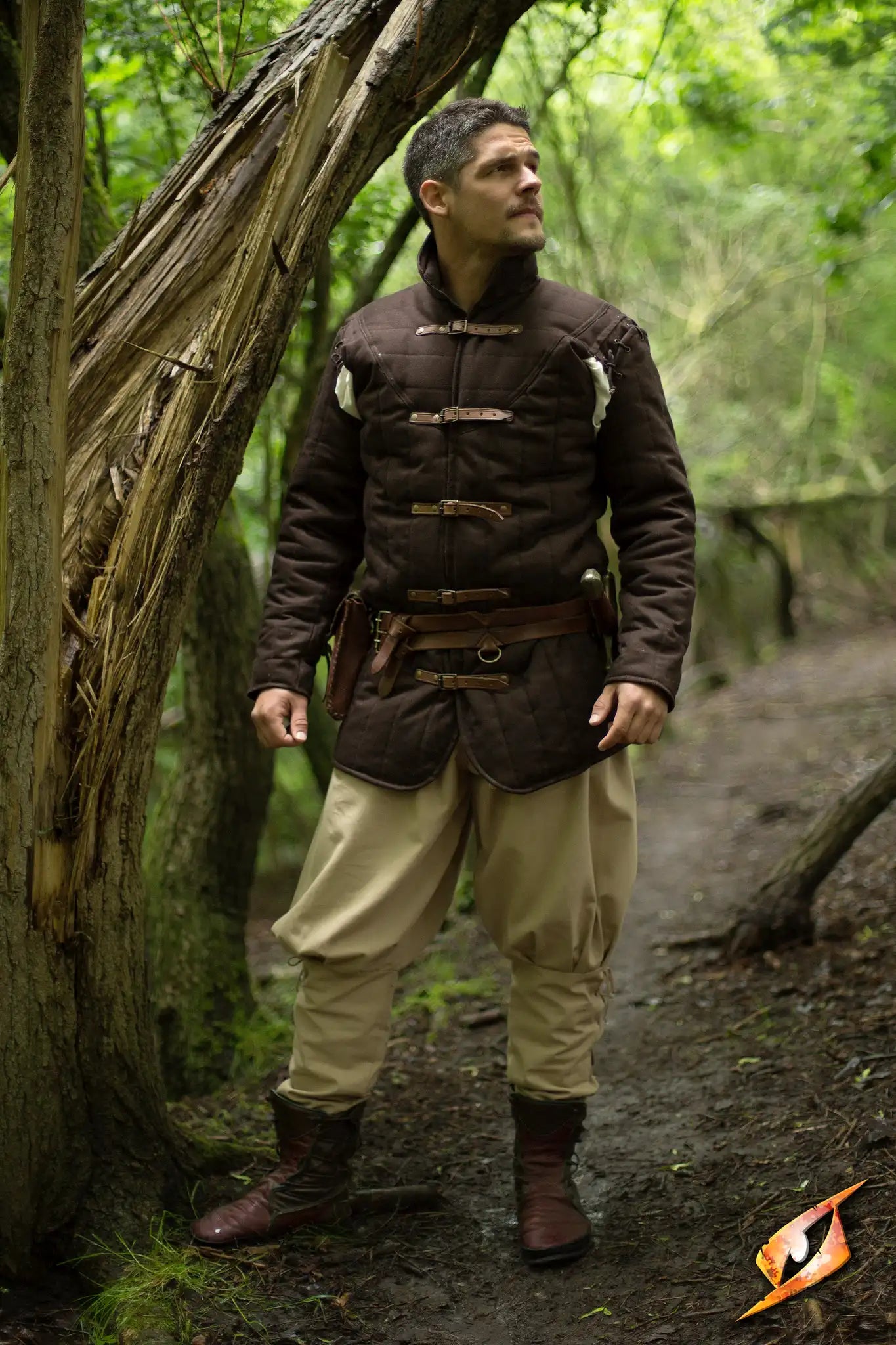 Gambeson Warrior With Long Sleeves standing in a forest, showcasing a dark protective garment.