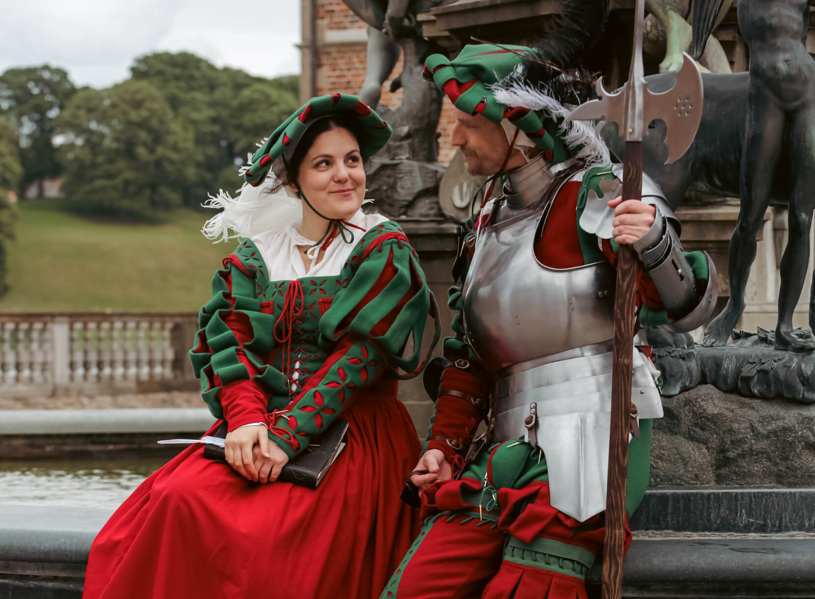 Couple in Landsknecht Renaissance costumes, the man wearing armor and holding an axe.
