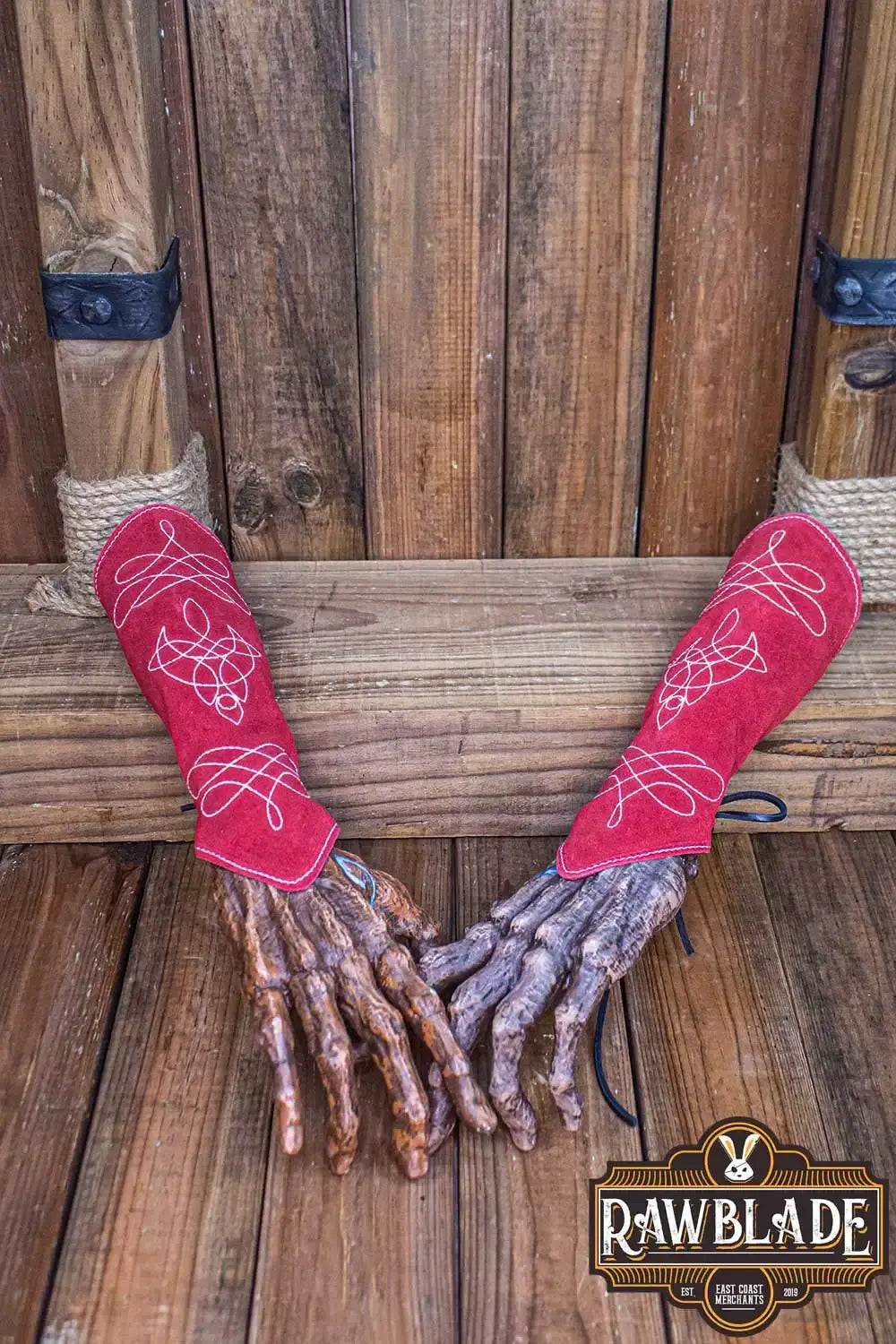 Vryla Premium Bracers displayed on wooden surface, featuring red split leather design and elven aesthetics.