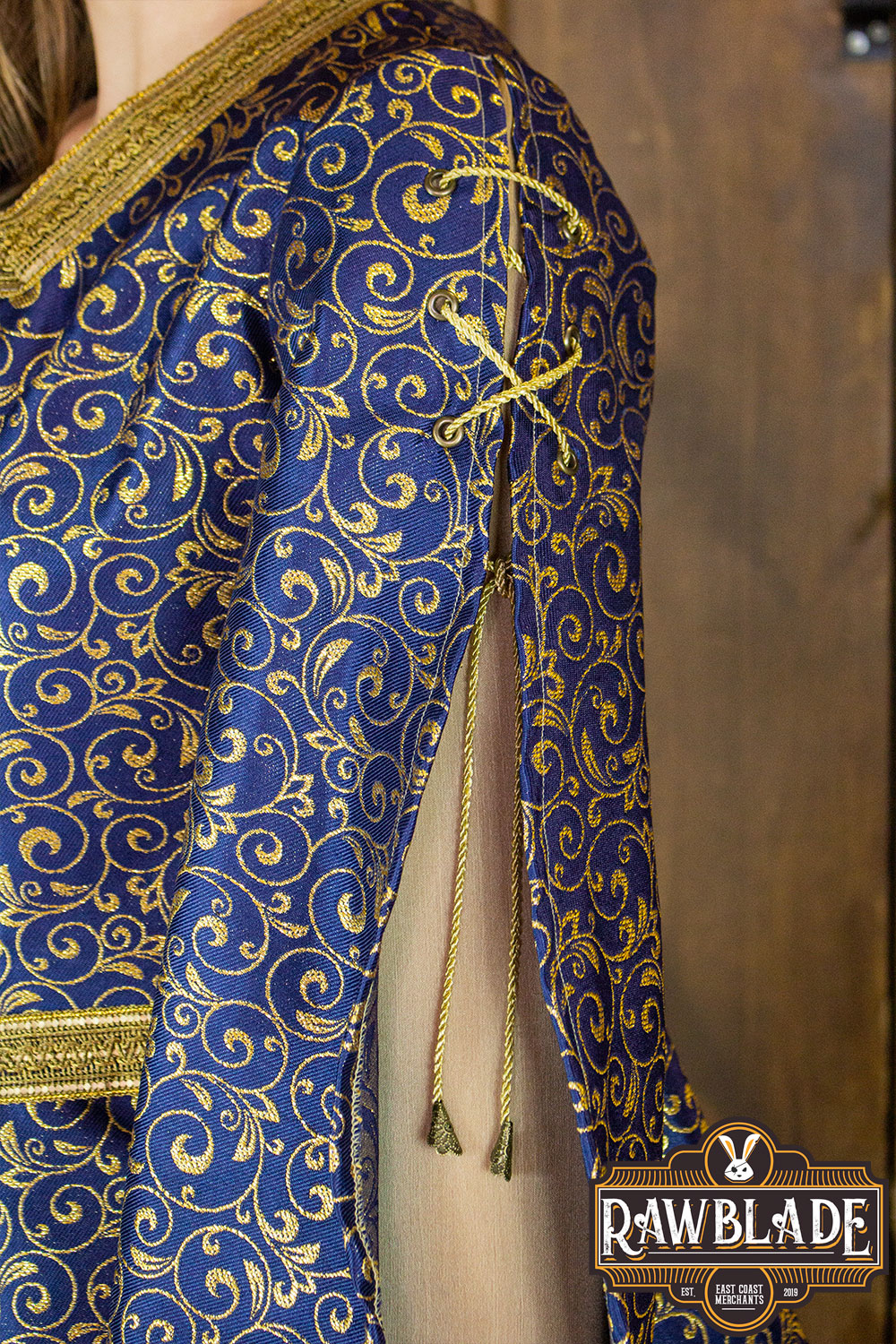 Aquitania Noble Dress featuring intricate gold trims and double tulle sleeves crafted from a luxurious gold brocade fabric.