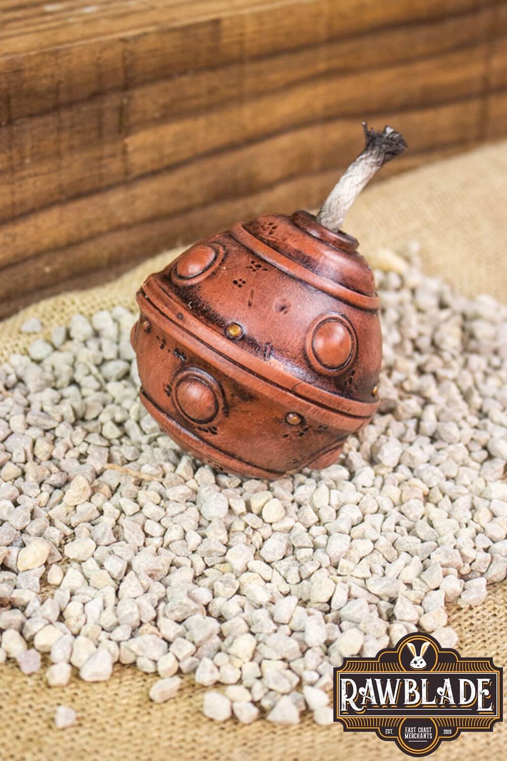 Realistic Breacher Bomb by Rawblade, handcrafted and safe, placed on textured surface with small stones.