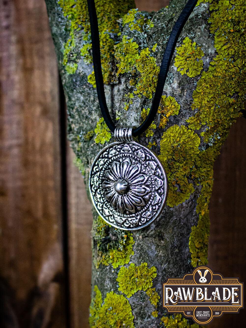 Capadocian Amulet featuring a circular silver pendant with floral motif, hanging on a black cord.