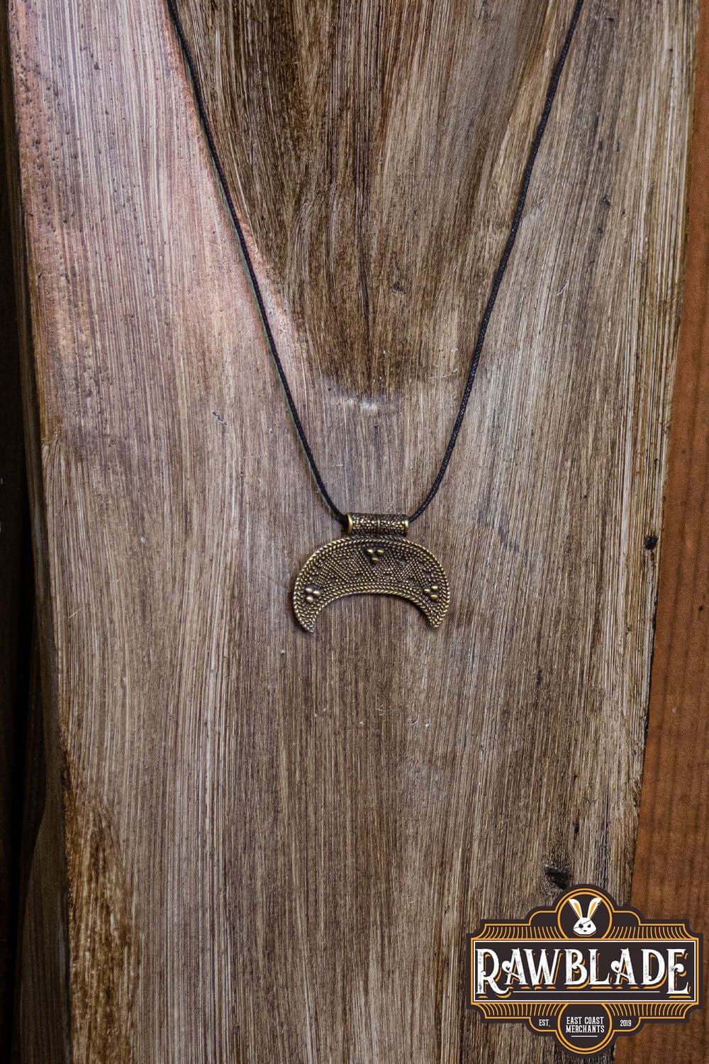 Western Lunula pendant displayed on wood, gold metal alloy with adjustable cord, perfect for everyday wear.