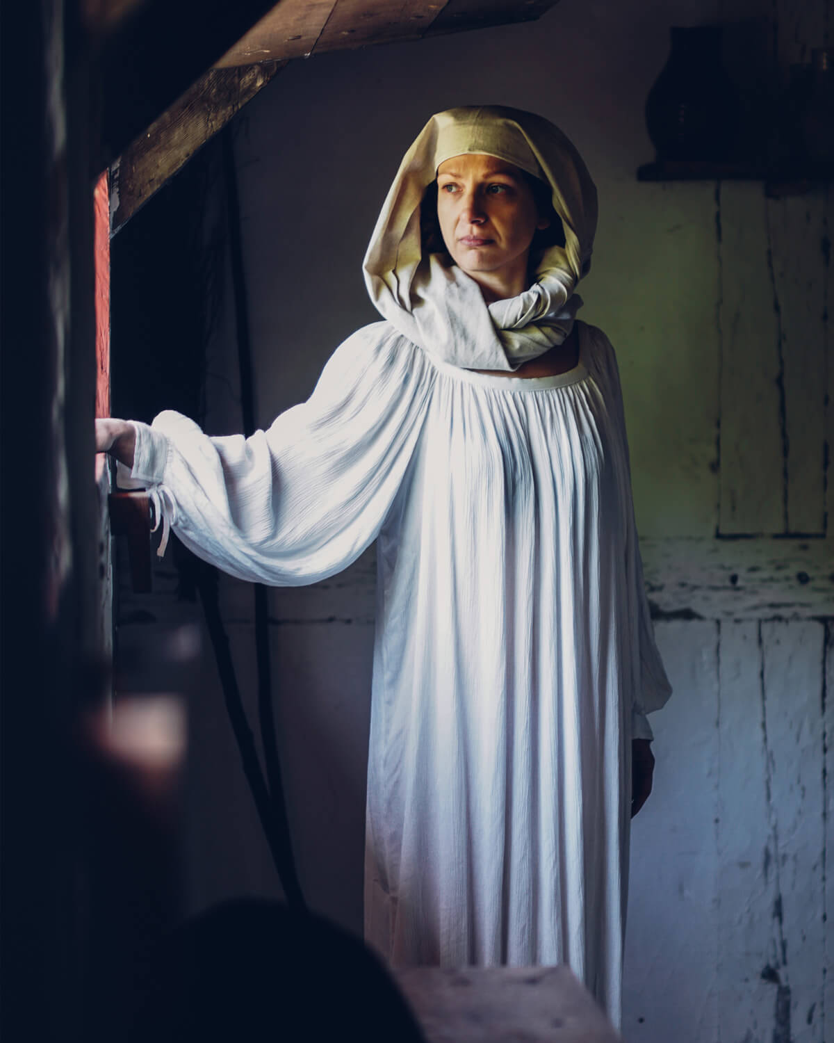 Woman in white medieval dress and hood with long sleeves