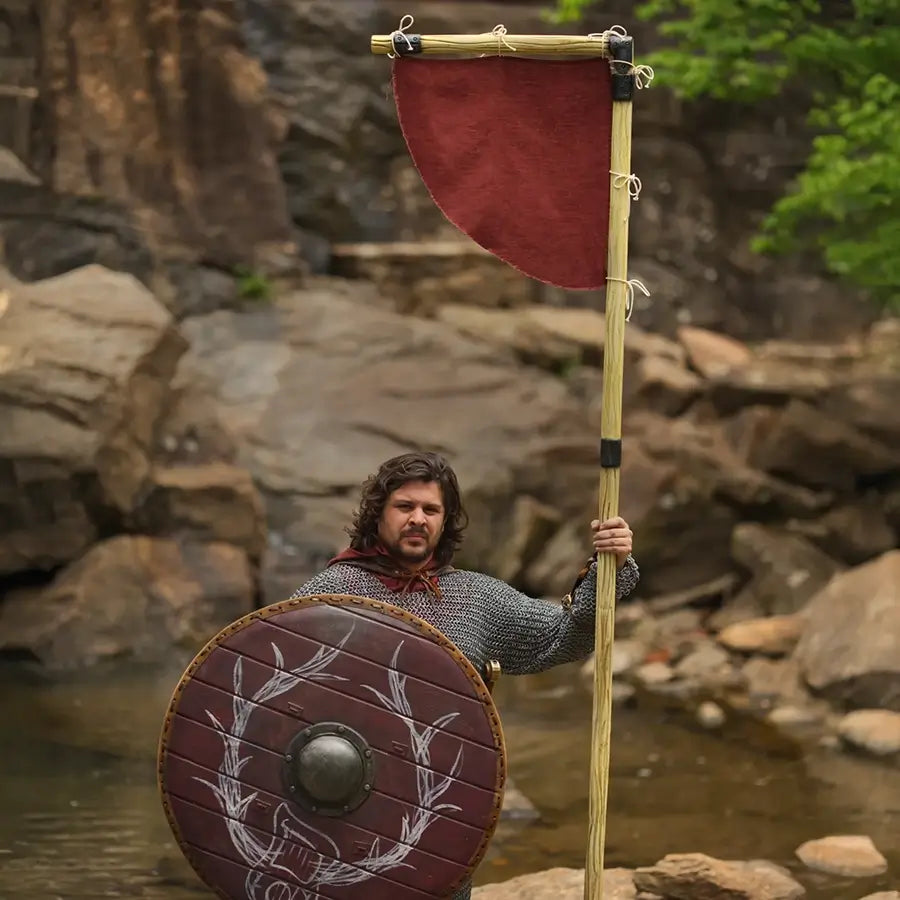 Viking warrior in chainmail with shield and red banner, medieval LARP gear.